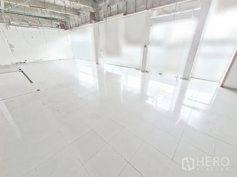 店屋 出租在Bang Na, Bangkok - 大面积开放楼层，亮面白砖，高挑顶与半透玻璃墙体。
