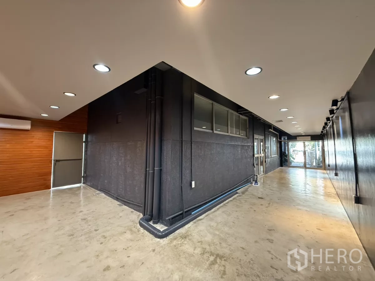Office Space for rent in Wang Thonglang, Bangkok - Broad passageway with black feature wall, ceiling spotlights and windows.