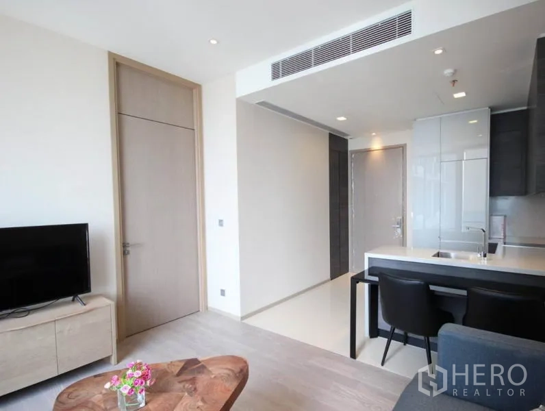 Condominium for rent in Watthana, Bangkok - Living area facing the entry and sleek kitchen with breakfast bar seating.