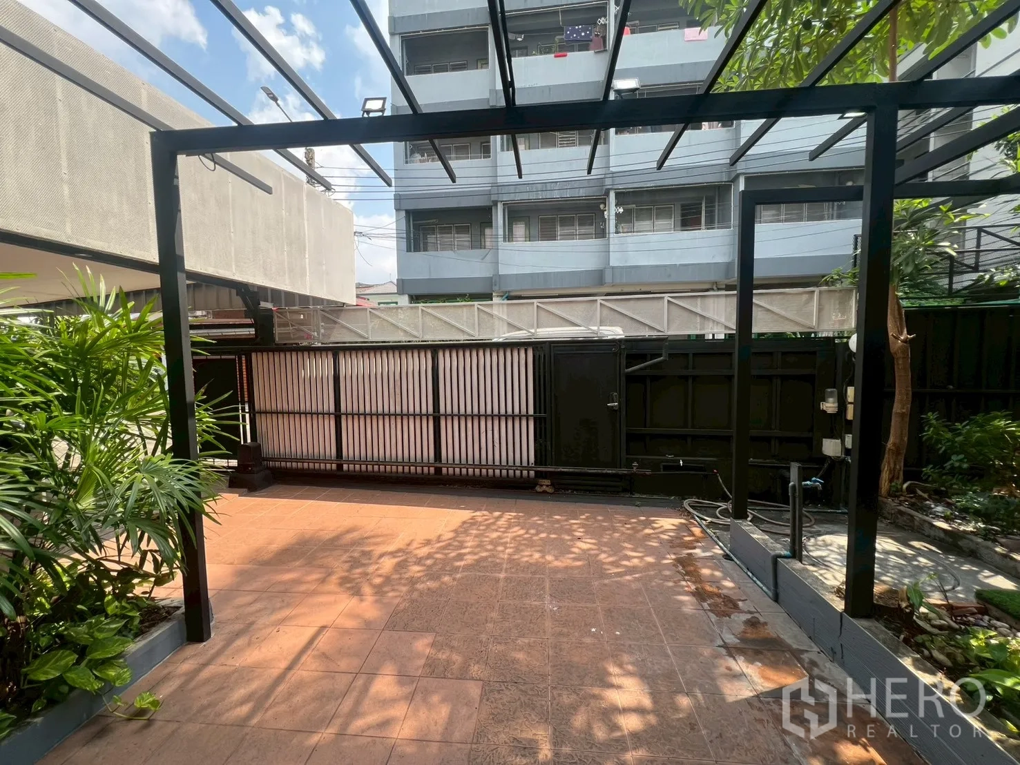 Detached House for rent or sale in Wang Thonglang, Bangkok - Front patio with pergola, tiled terrace and tropical plants.
