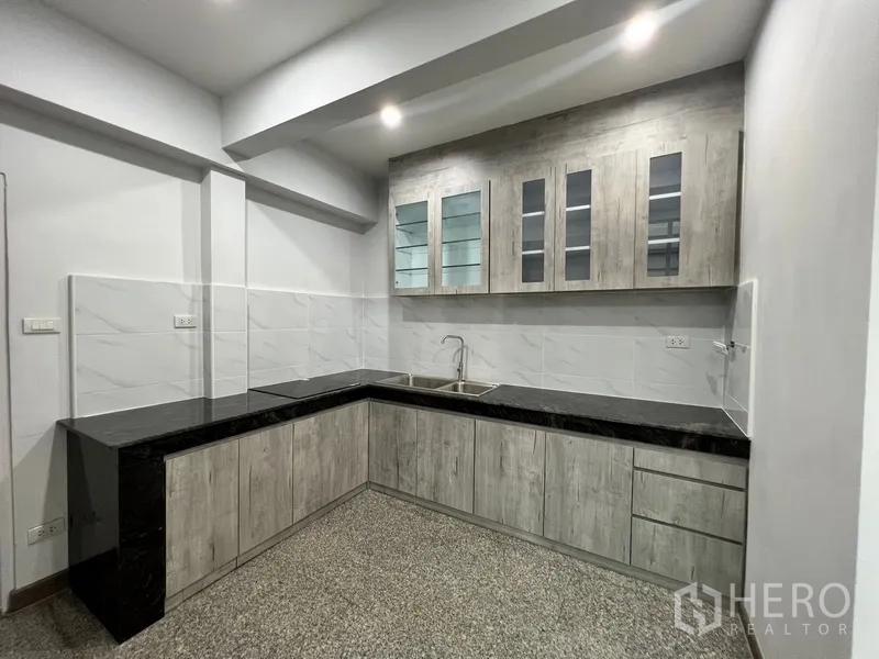 带办公室的家 出租在Watthana, Bangkok - 现代L形厨房，花岗岩台面与玻璃门吊柜。