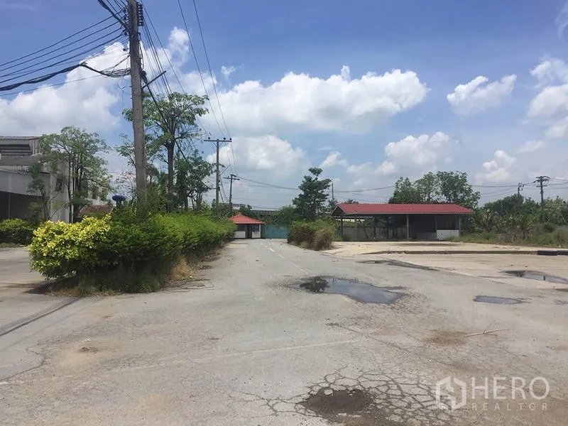 Office Space for rent in Sai Noi, Nonthaburi - Internal road and parking court with greenery and red‑roof shelters in a quiet compound.