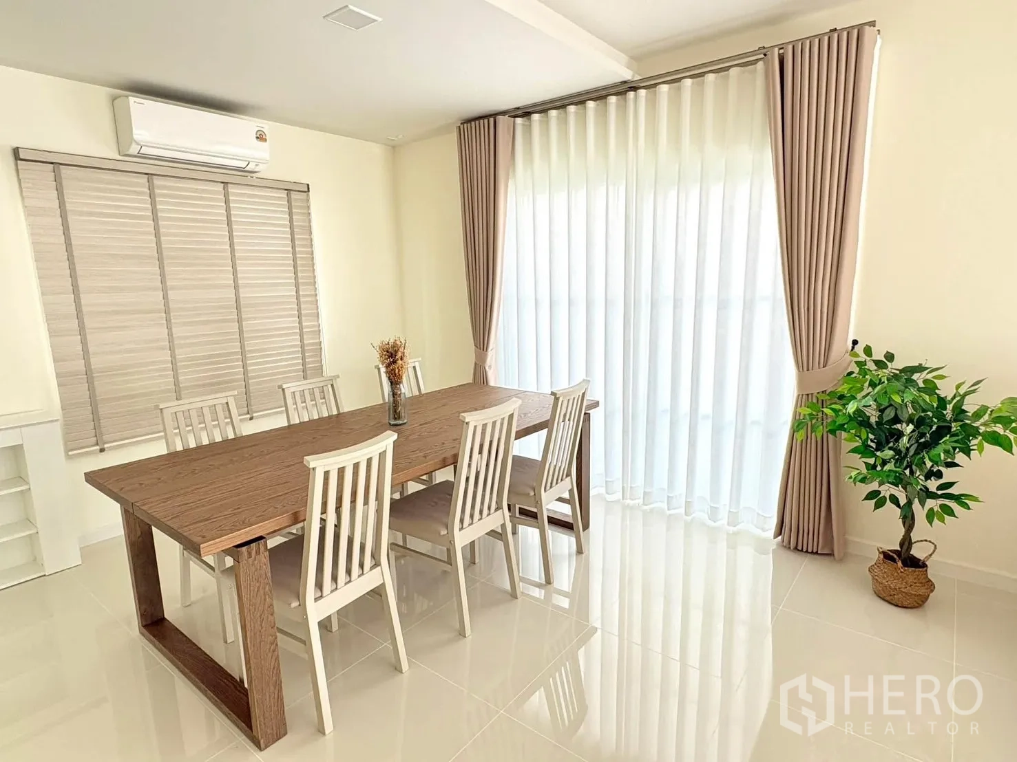 独立式住宅 for rent in Bang Phli, Samut Prakan - 餐厅配六人木餐桌、白色椅子与落地窗帘。