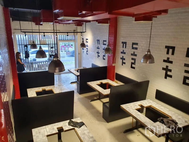 อาคารพาณิชย์ ให้เช่าในKhlong Toei, Bangkok - ภายในร้านอาหารแบบบูธที่นั่ง โต๊ะเตาย่าง ผนังกระเบื้องสีขาว และท่อลมสีแดงบนเพดาน