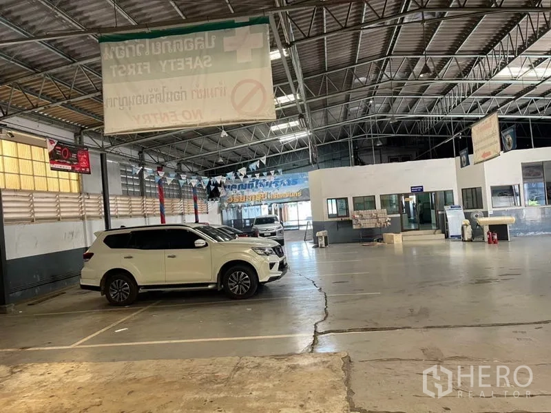 货栈 出租在Prawet, Bangkok - 仓库内的室内停车与装卸区，位于钢桁架屋顶下。