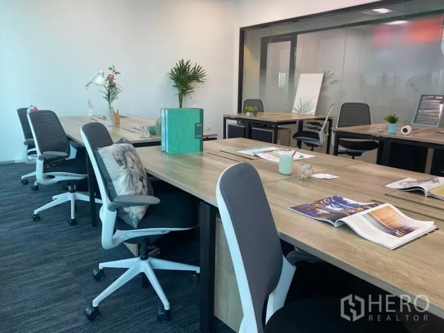 Office Space for rent in Sathon, Bangkok - Row of shared desks with office chairs and a glass-walled meeting room in the background.