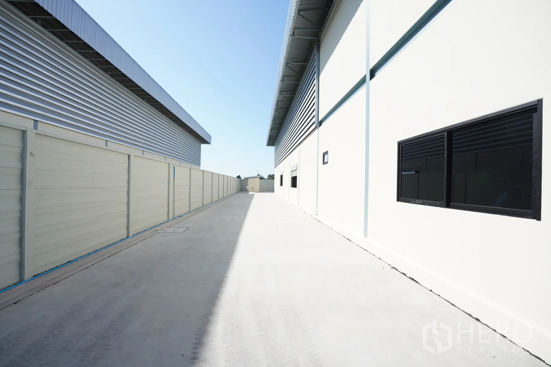 Factory for rent in Mueang Samut Prakan, Samut Prakan - Long concrete side driveway beside the factory and high perimeter wall.