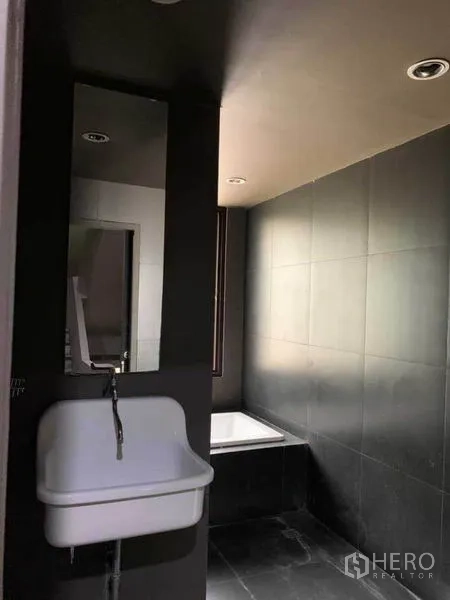 สำนักงานที่บ้าน ให้เช่าในHuai Khwang, Bangkok - ห้องน้ำปูกระเบื้องสีเข้มพร้อมอ่างอาบน้ำและอ่างล้างหน้าแขวนผนัง.