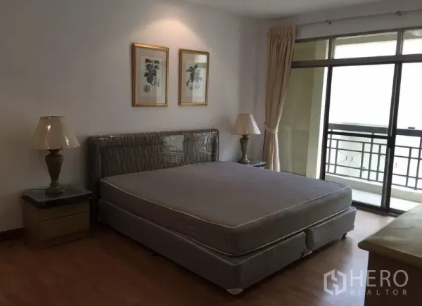 คอนโด ให้เช่าหรือขายในWatthana, Bangkok - ห้องนอนหลักเตียงคิงไซส์ โคมไฟข้างเตียง และประตูกระจกสไลด์ออกสู่ระเบียง