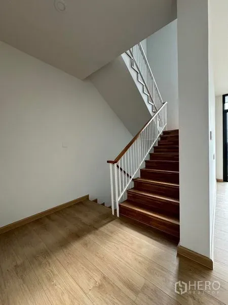 Home Office for rent in Pak Kret, Nonthaburi - Wood staircase with white railing leading from the ground floor in a home office