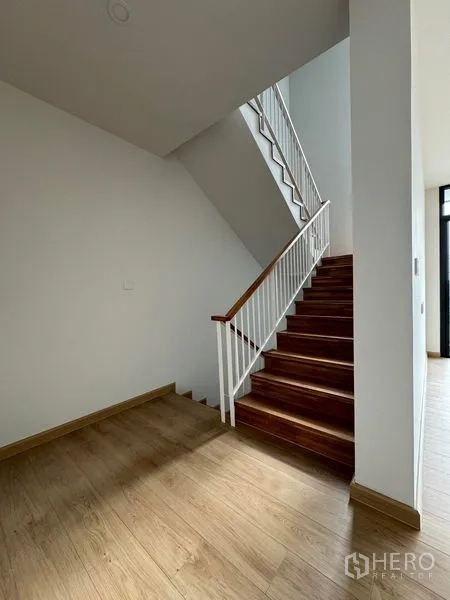 Home Office for rent in Pak Kret, Nonthaburi - Wood staircase with white railing leading from the ground floor in a home office