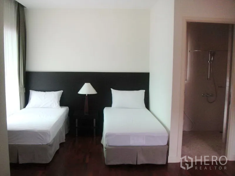 Detached House for rent in Wang Thonglang, Bangkok - Twin bedroom with ensuite shower and large curtained windows.