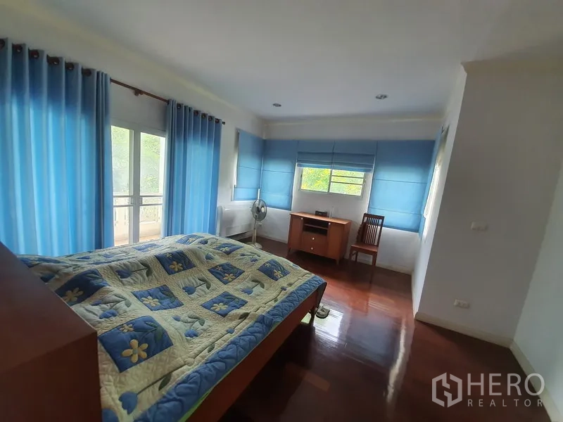 บ้าน ให้เช่าในLat Krabang, Bangkok - ห้องนอนใหญ่กว้าง ผ้าม่านสีน้ำเงิน ทางออกระเบียง และพื้นไม้ขัดมัน.