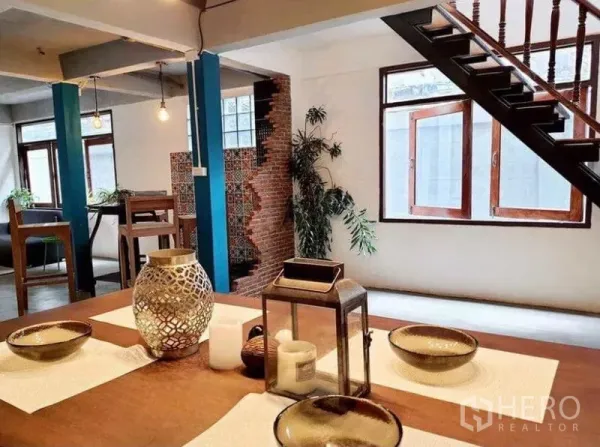 Detached House for rent in Pathum Wan, Bangkok - Open-plan space with wooden staircase, dining table and brick wall with patterned tiles