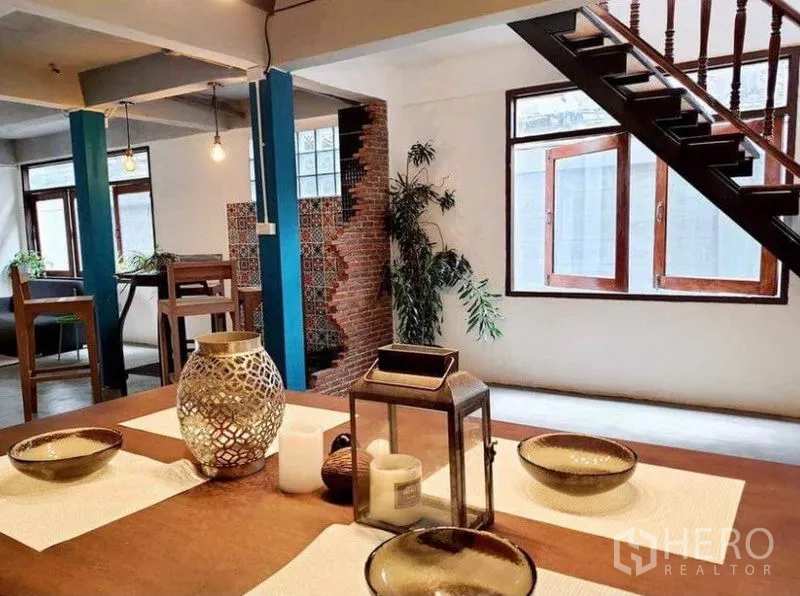 Detached House for rent in Pathum Wan, Bangkok - Open-plan space with wooden staircase, dining table and brick wall with patterned tiles