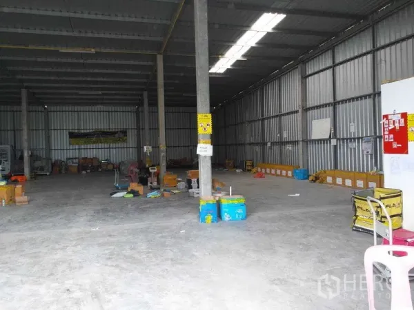 Warehouse for rent in Pak Kret, Nonthaburi - Interior view with steel walls, support columns, and clear-span floor space for storage.