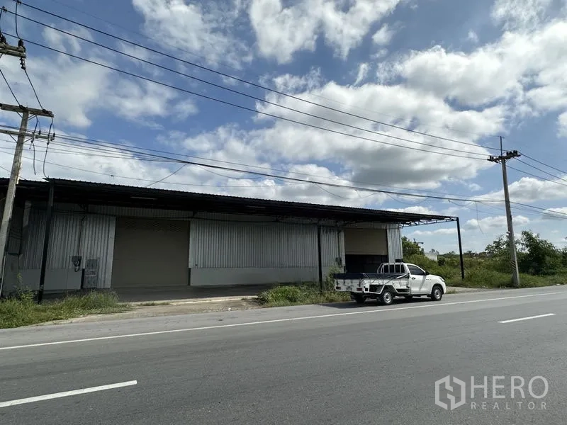 货栈 出租在Khlong Luang, Pathum Thani - 巴吞他尼府空銮县临路仓库外立面，金属墙板，装卸区与皮卡车。