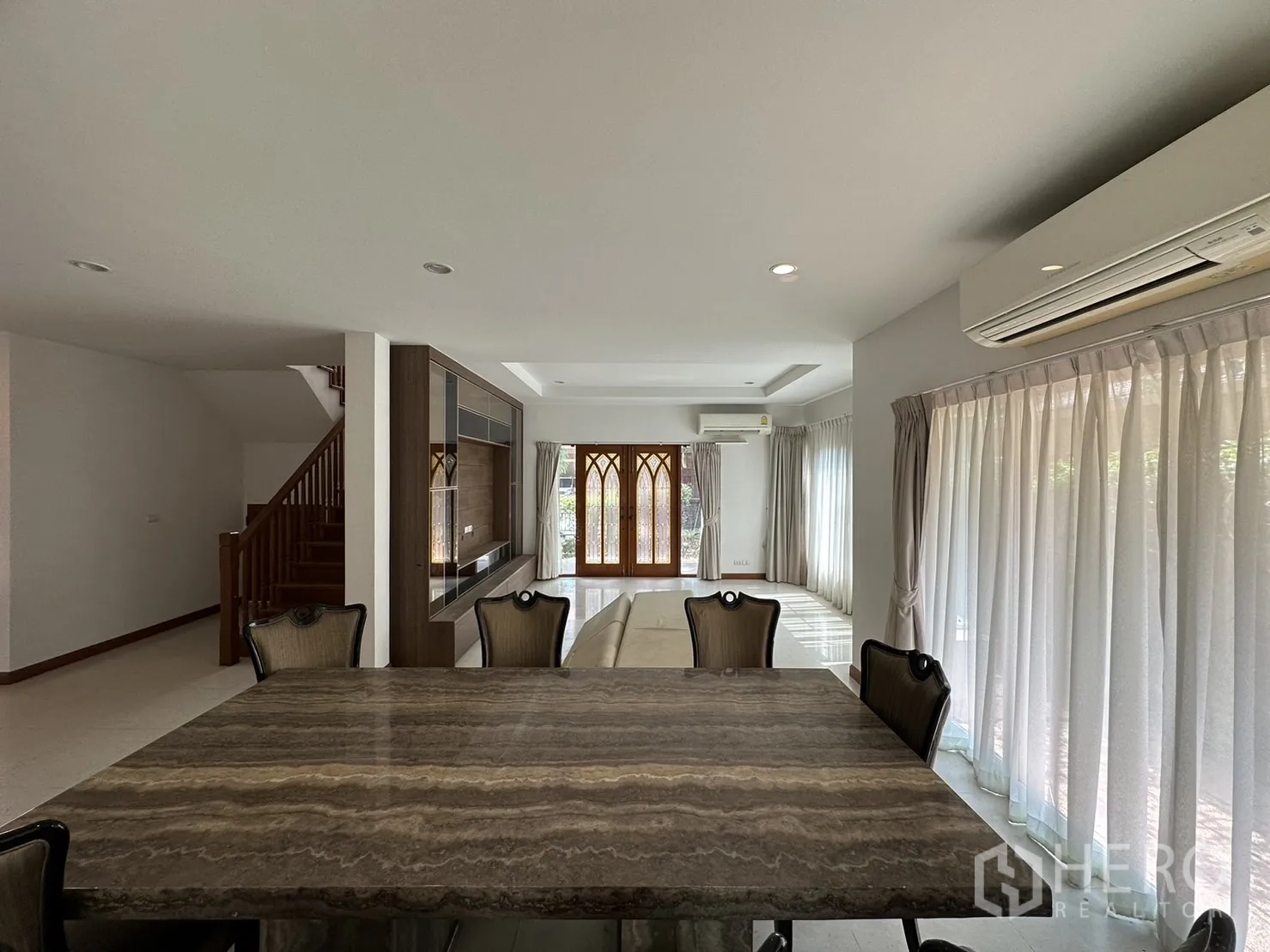 Detached House for rent or sale in Pak Kret, Nonthaburi - Dining zone with floor-to-ceiling curtains and split air conditioner facing the garden.
