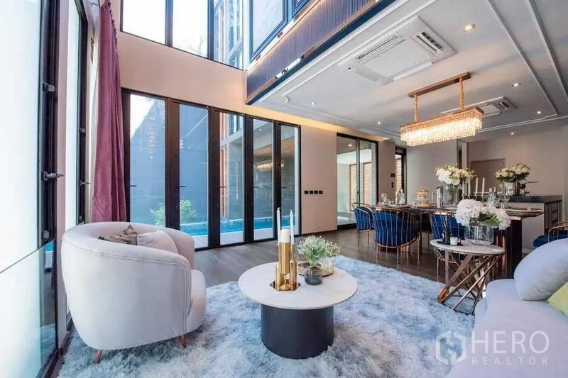 独立式住宅 出售在Prawet, Bangkok - 挑高双层客厅与餐厅，落地玻璃门通向私家泳池。