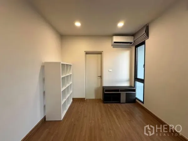 Detached House for rent in Bang Phli, Samut Prakan - Bright multipurpose room with wood flooring, shelving, window and wall-mounted air conditioner.