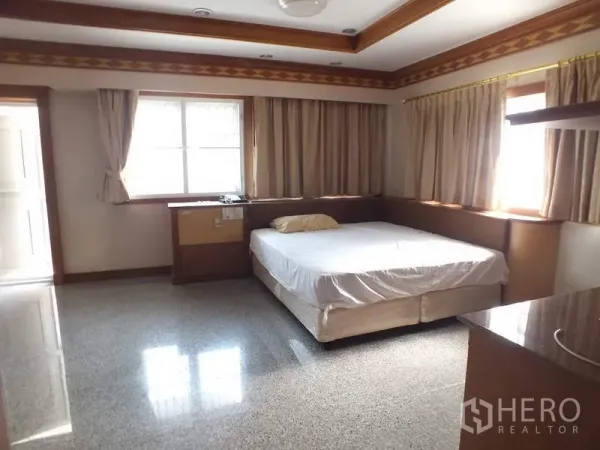 Detached House for rent in Bang Rak, Bangkok - Bright bedroom with double bed, wood trim, multiple curtained windows and glossy stone flooring.