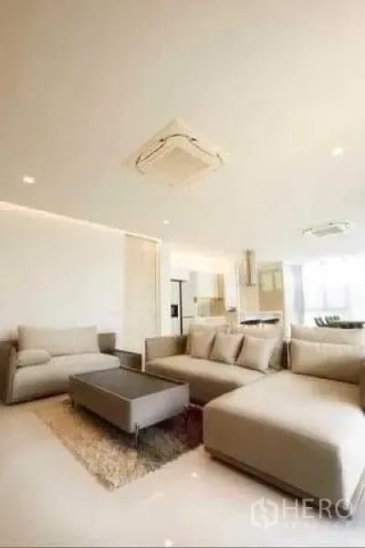 联排别墅 出租在Huai Khwang, Bangkok - 宽敞起居区，组合沙发与地毯，与开放式厨房餐厅相连。