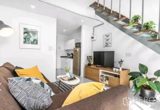 ทาวน์เฮาส์ ให้เช่าในKhlong Toei, Bangkok - มุมห้องนั่งเล่น ตู้ทีวี ต้นไม้กระถาง และครัวใต้บันได