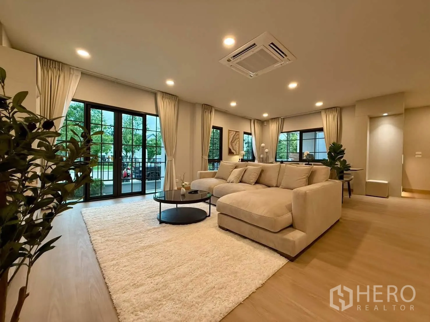 独栋房屋 for rent in Bang Phli, Samut Prakan - 开放式起居区，大型转角沙发、地毯与通高窗。