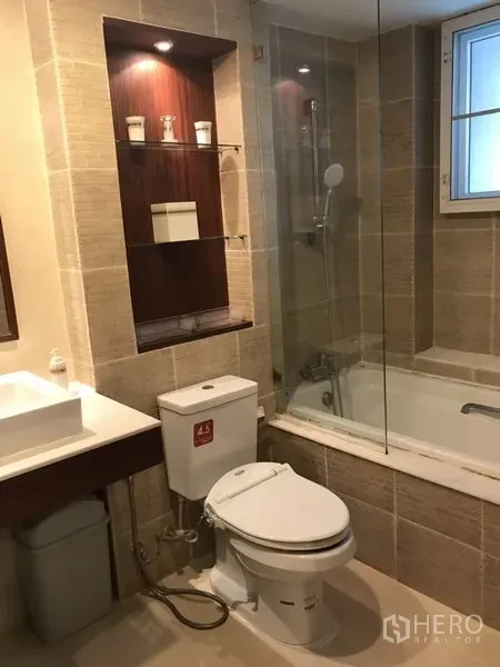 Condominium for rent in Watthana, Bangkok - Modern bathroom with bathtub and glass screen, vanity sink and tiled walls.