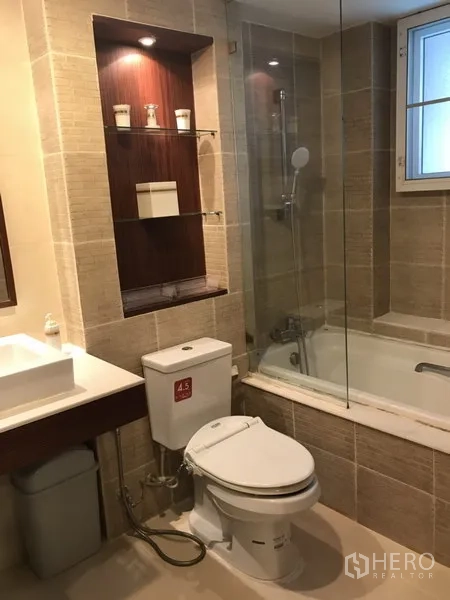 Condominium for rent in Watthana, Bangkok - Modern bathroom with bathtub and glass screen, vanity sink and tiled walls.