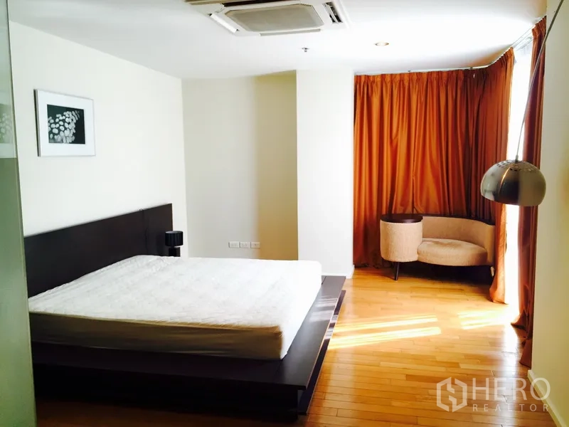 公寓 出租在Bang Rak, Bangkok - 采光充足的主卧，木地板与转角休闲椅及整窗窗帘。