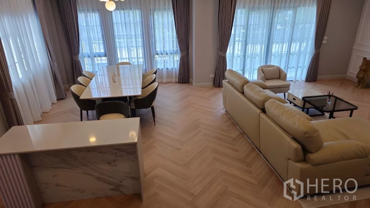 Detached House for rent or sale in Bang Phli, Samut Prakan - View over the lounge and dining zone showing floor-to-ceiling windows, drapes and a marble-topped island.