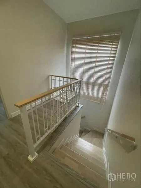 บ้าน ขายในLat Krabang, Bangkok - โถงบันไดไม้พร้อมราวสีขาวและหน้าต่างบานใหญ่ติดมู่ลี่