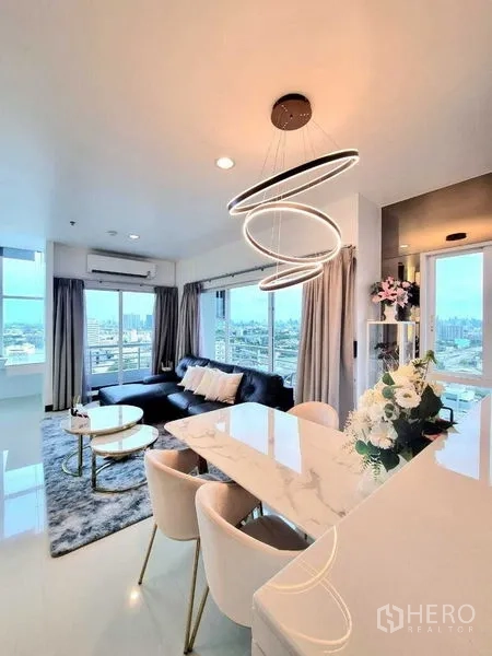 คอนโด ขาย - พื้นที่นั่งเล่นและทานอาหารแบบเปิดโล่ง โคมไฟเด่น และหน้าต่างกว้างเห็นวิวเมือง