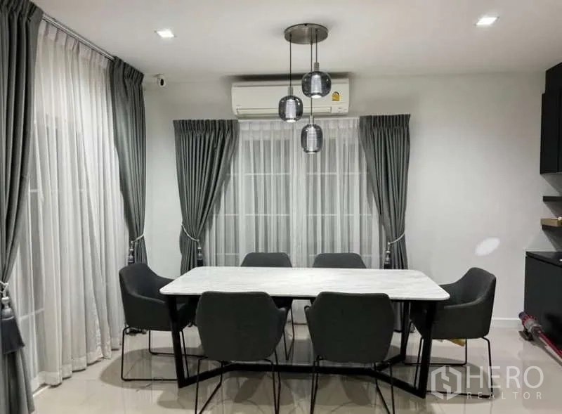 Detached House for rent in Bueng Kum, Bangkok - Dining area for six with pendant lights and floor-to-ceiling curtains.