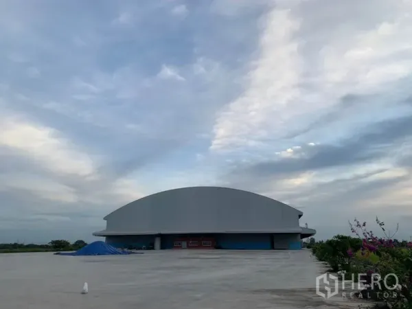 คลังสินค้า ให้เช่าในSai Noi, Nonthaburi - ลานคอนกรีตกว้างและอาคารโกดังหลังคาโค้งภายนอกใต้ท้องฟ้า ไทรน้อย นนทบุรี