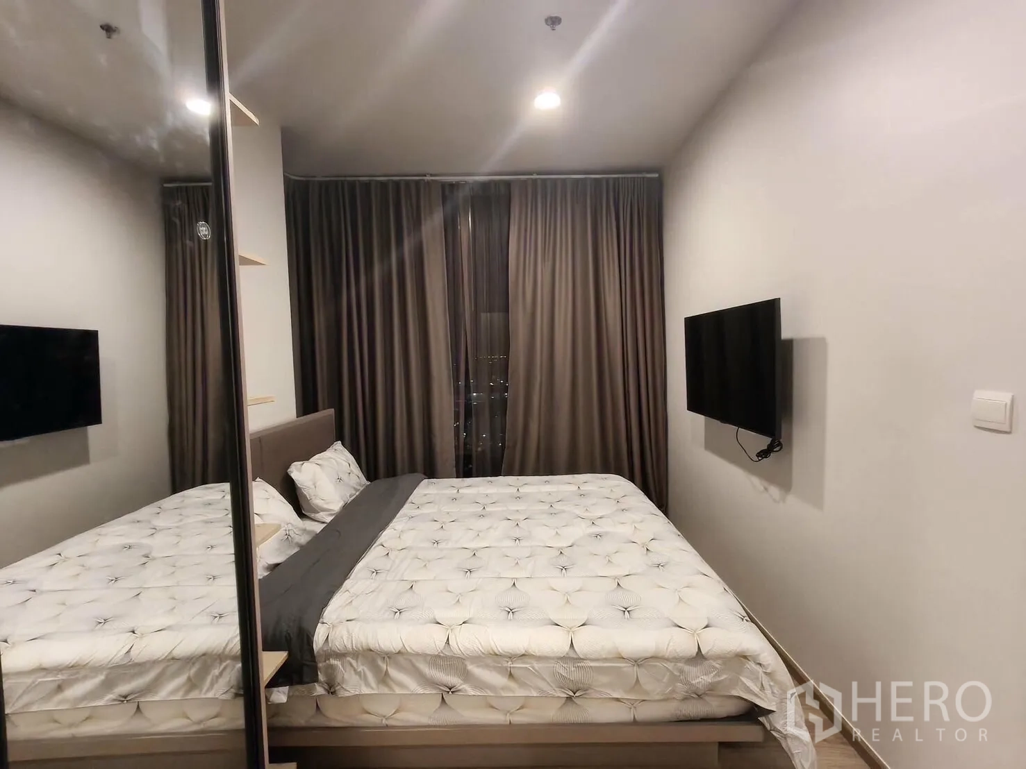 คอนโด for rent in Khlong Toei, Bangkok - ห้องนอนหลักเตียงใหญ่ ทีวีติดผนัง ตู้เสื้อผ้าบานกระจก และผ้าม่านทึบ