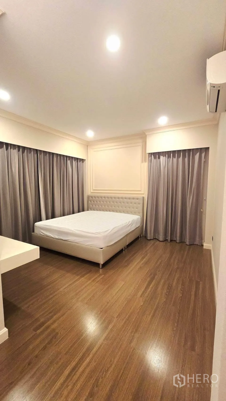 Detached House for rent in Prawet, Bangkok - Spacious bedroom with upholstered bed, recessed lights and grey curtains.