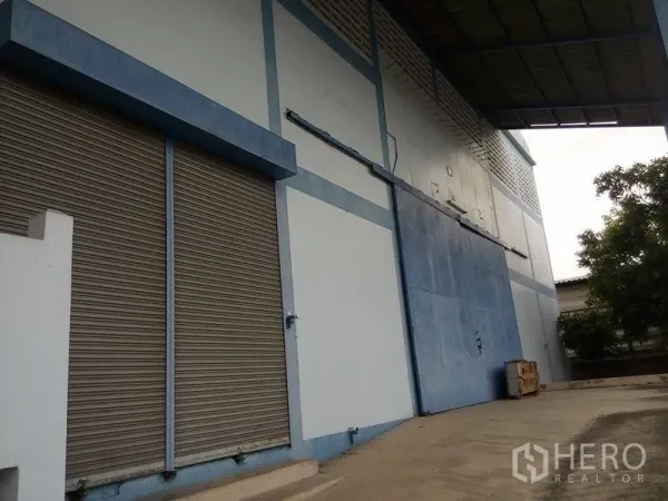 Warehouse for rent in Min Buri, Bangkok - Warehouse exterior with roller shutter doors and a covered loading bay.