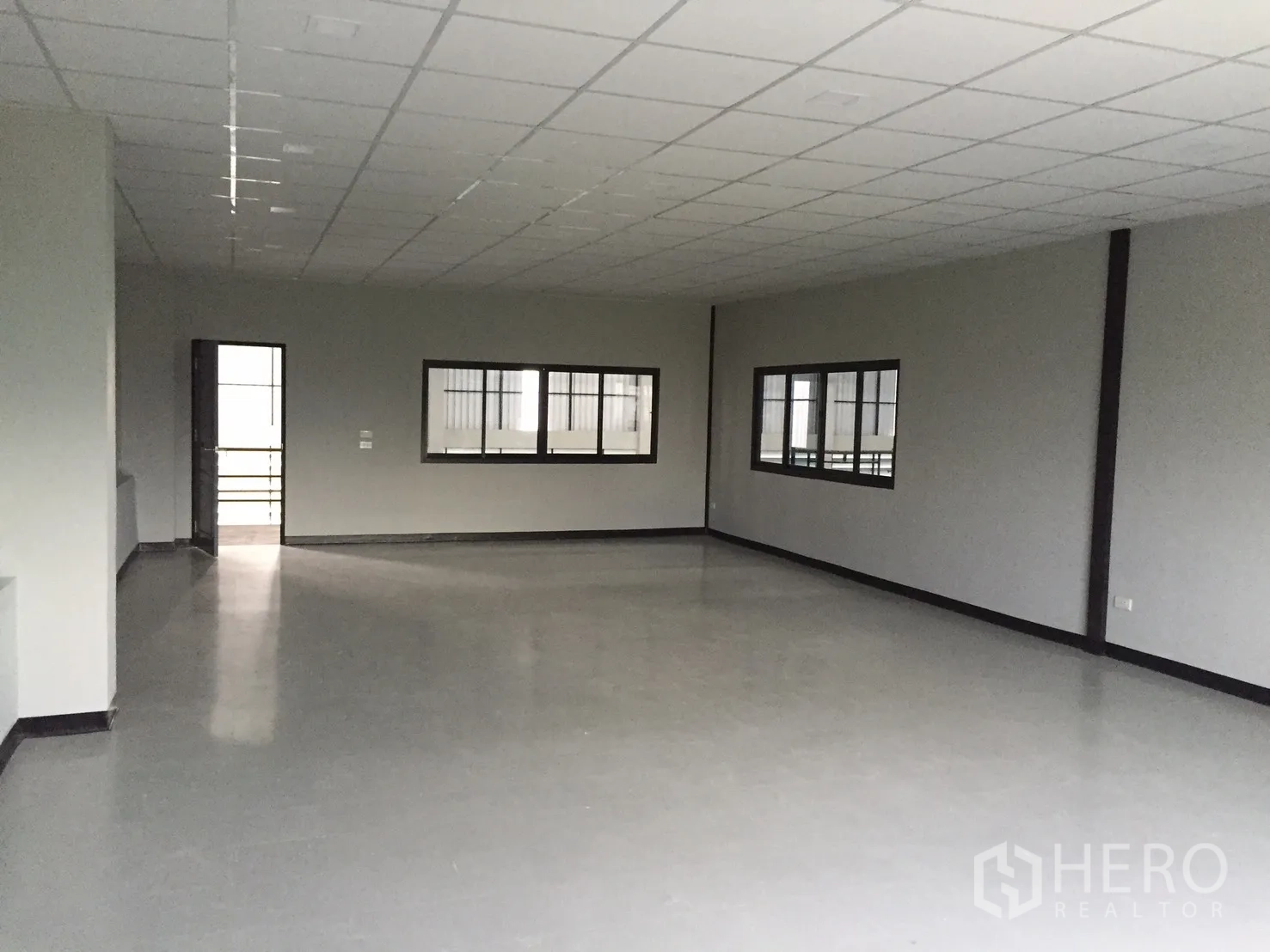 Warehouse for rent in Bang Phli, Samut Prakan - Large empty office room with windows, suspended ceiling and smooth flooring.