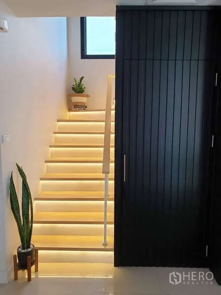 Detached House for sale in Bang Phli, Samut Prakan - Staircase with warm LED step lighting beside a black storage cabinet