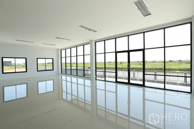Factory for rent or sale in Bang Bo, Samut Prakan - Bright second-floor office with floor-to-ceiling windows overlooking greenery.