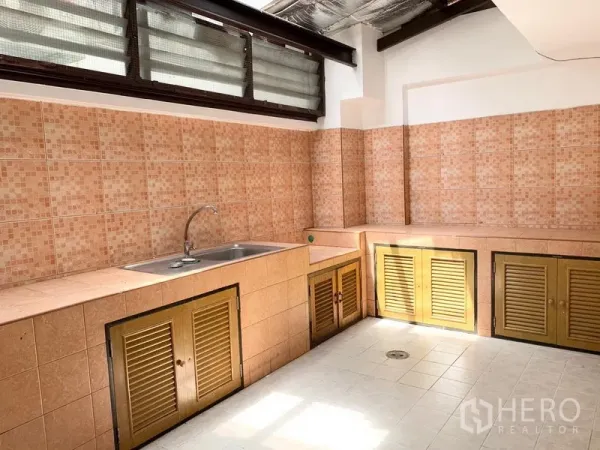 联排别墅 出租在Khlong Toei, Bangkok - 泰式厨房，粉色马赛克瓷砖台面，不锈钢水槽与百叶柜门，高窗采光。