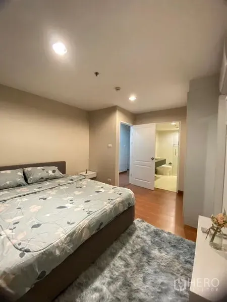 Condominium for rent - Master bedroom in Bangkok condo with king bed, wood floors, rug, and doorway to an ensuite bathroom.