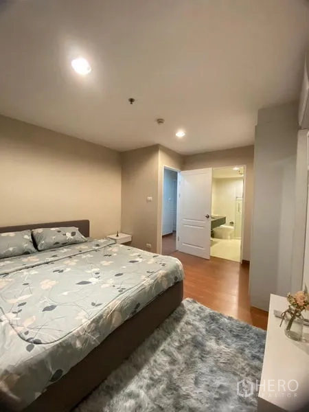 Condominium for rent - Master bedroom in Bangkok condo with king bed, wood floors, rug, and doorway to an ensuite bathroom.