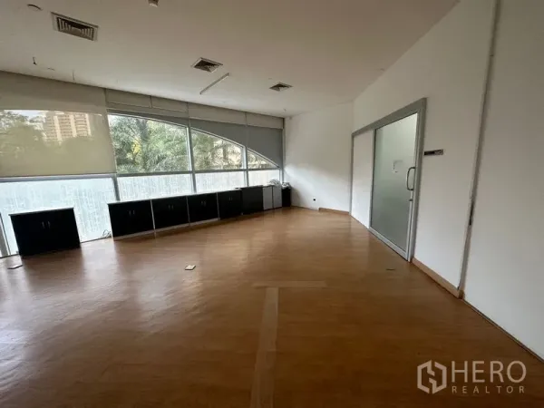 办公空间 出租在Pathum Wan, Bangkok - 转角办公室，木地板，弧形落地窗配百叶帘，旁有玻璃会议室门。