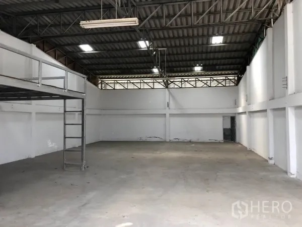 货栈 出租或出售在Khlong Luang, Pathum Thani - 仓库内部，高挑钢梁屋顶，顶灯明亮，混凝土地面，带梯子的夹层平台