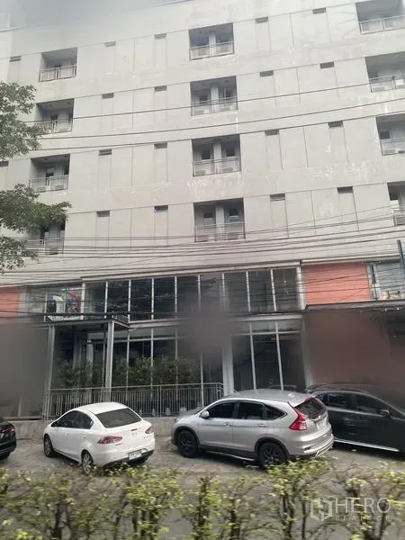 零售空间 出租在Watthana, Bangkok - 街景现代建筑，一层为玻璃商铺，路边停放车辆