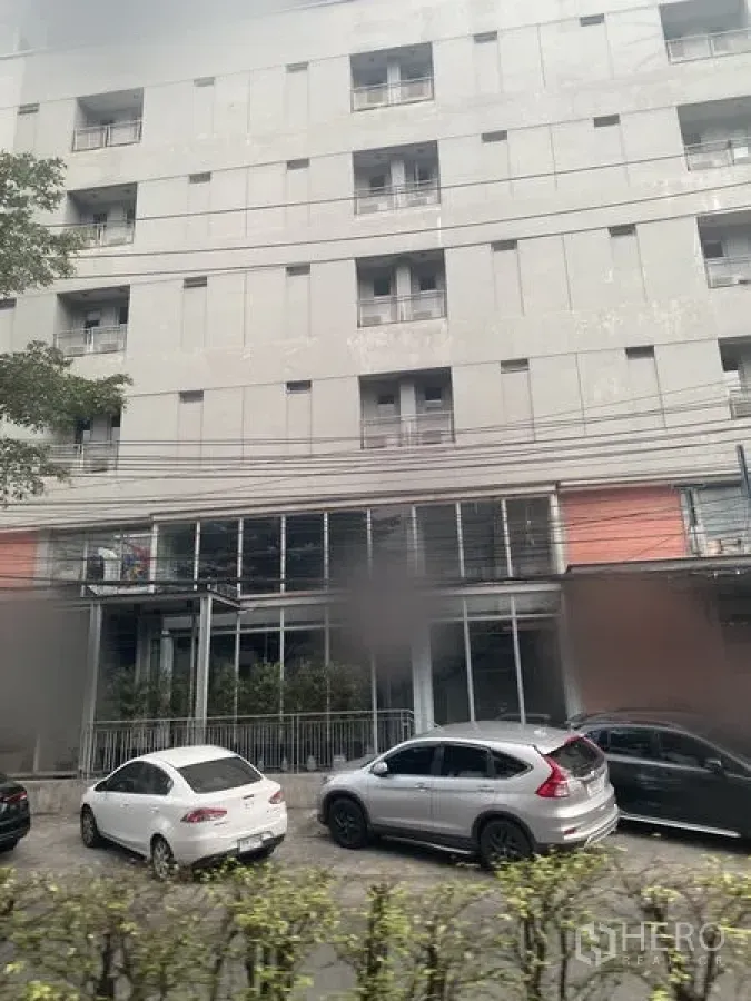 零售空间 出租在Watthana, Bangkok - 街景现代建筑，一层为玻璃商铺，路边停放车辆