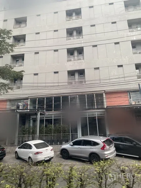 零售空间 出租在Watthana, Bangkok - 街景现代建筑，一层为玻璃商铺，路边停放车辆